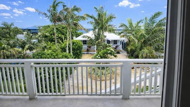 A balcony with a view of a white house surrounded by palm trees and greenery. - 'Bentwood Escape' 
Modern unit in heart of Yamba (Yamba)