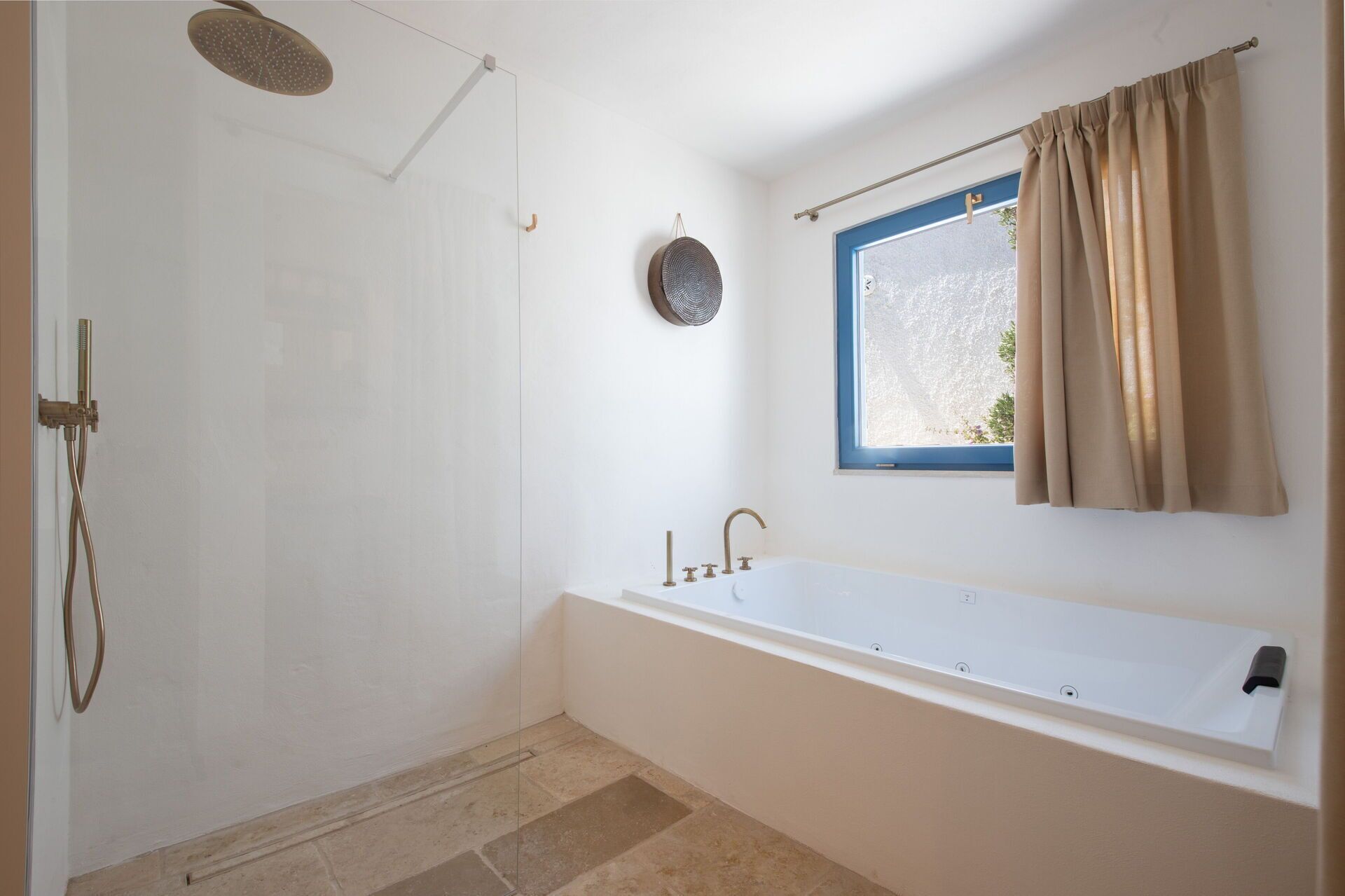 Een badkamer met een bad, een douche en een raam met gordijnen.