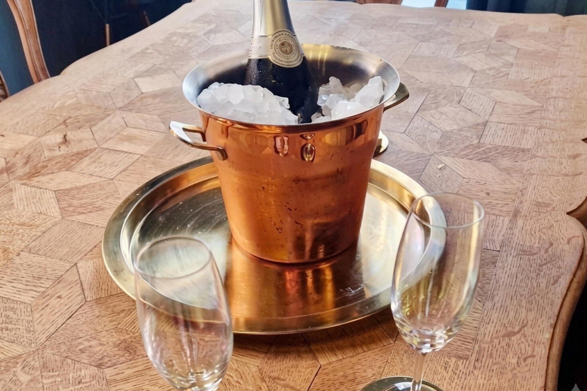 Ett kopparbadkar fyllt med is, två glas och ett bricka på ett träbord.