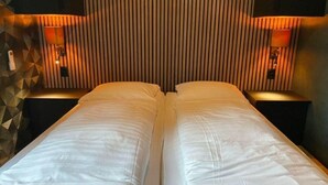 Cama doble con ropa blanca en una habitación de hotel.