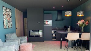 Una cocina moderna con horno empotrado, un área de comedor con dos sillas y un suelo con estampado tipo espiga.
