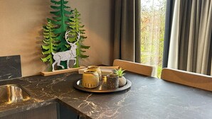 Una cocina moderna con encimera de mármol, un árbol decorativo con un ciervo, y una bandeja con frascos y una piña.