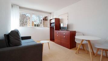 Ein modernes Wohnzimmer mit einer Couch, einem Fernseher, einem Holzschrank und einem kleinen runden Tisch.