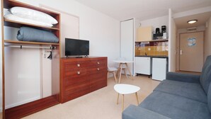 En kompakt bolig med sofa, fjernsyn, tekøkken og garderobe.