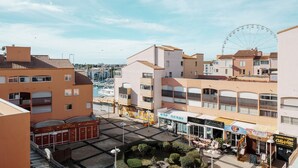 A coastal town with a Ferris wheel, waterfront buildings, and a sushi restaurant. - Lush corner near the local bistro (Agde)