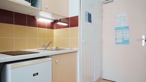 A compact kitchen with a sink, a small refrigerator, and a door with a paper holder. - Lush corner near the local bistro (Agde)