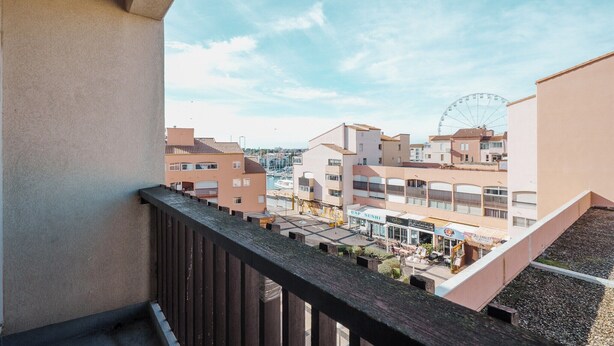 A balcony with a view of a cityscape, including buildings and a Ferris wheel. - Lush corner near the local bistro (Agde)
