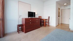 Una habitación con un aparador de madera, un televisor, una mesa de comedor con sillas y suelo alfombrado.