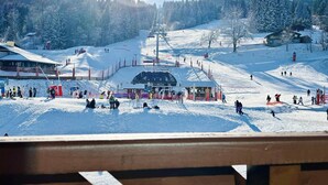 Une station de ski dotée d’un télésiège, d’arbres couverts de neige et d’une plateforme d’observation en bois.