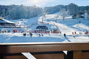 Ein Skigebiet mit Seilbahn, schneebedeckten Bäumen und einer hölzernen Aussichtsplattform.