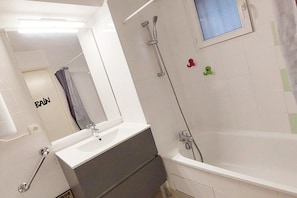Uma casa de banho com banheira, lavatório, espelho, chuveiro e sanita.