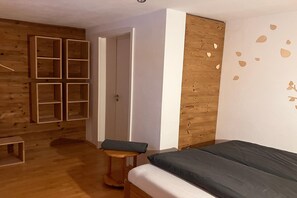 Habitació amb un llit, una banca de fusta i un armari amb diverses prestatgeries.