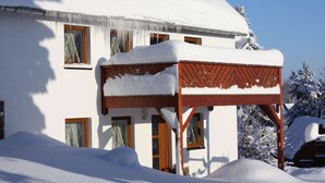 A snow-covered building with a wooden structure in front. - Haus De Kleene & Gruusse in Mildenau (Mildenau)