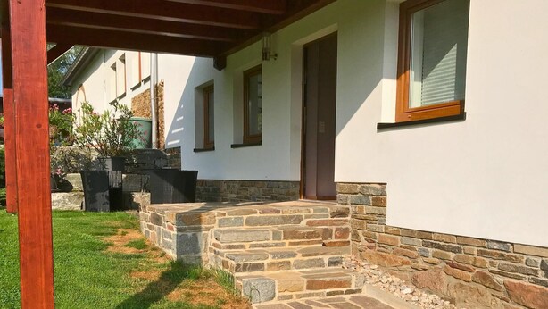 A house with a stone staircase leading to a door, a wooden pergola, and a stone wall. - Haus De Kleene & Gruusse in Mildenau (Mildenau)