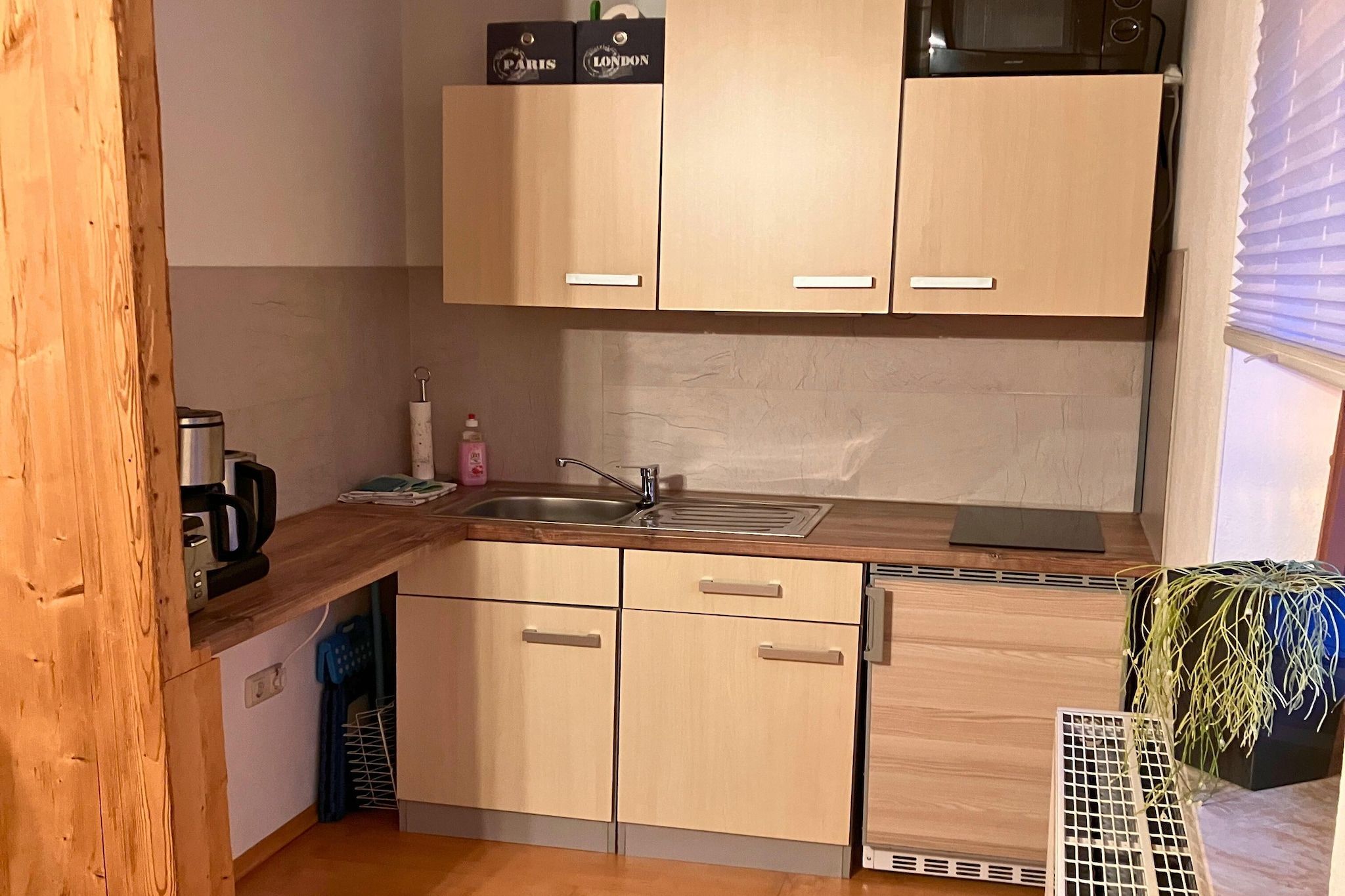 A compact kitchen with wooden cabinets, a sink, and a microwave.