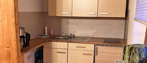 A compact kitchen with wooden cabinets, a sink, and a microwave.