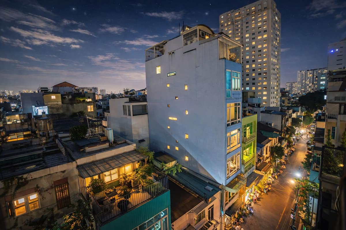A cityscape at night with modern buildings, a rooftop garden, and a busy street below.