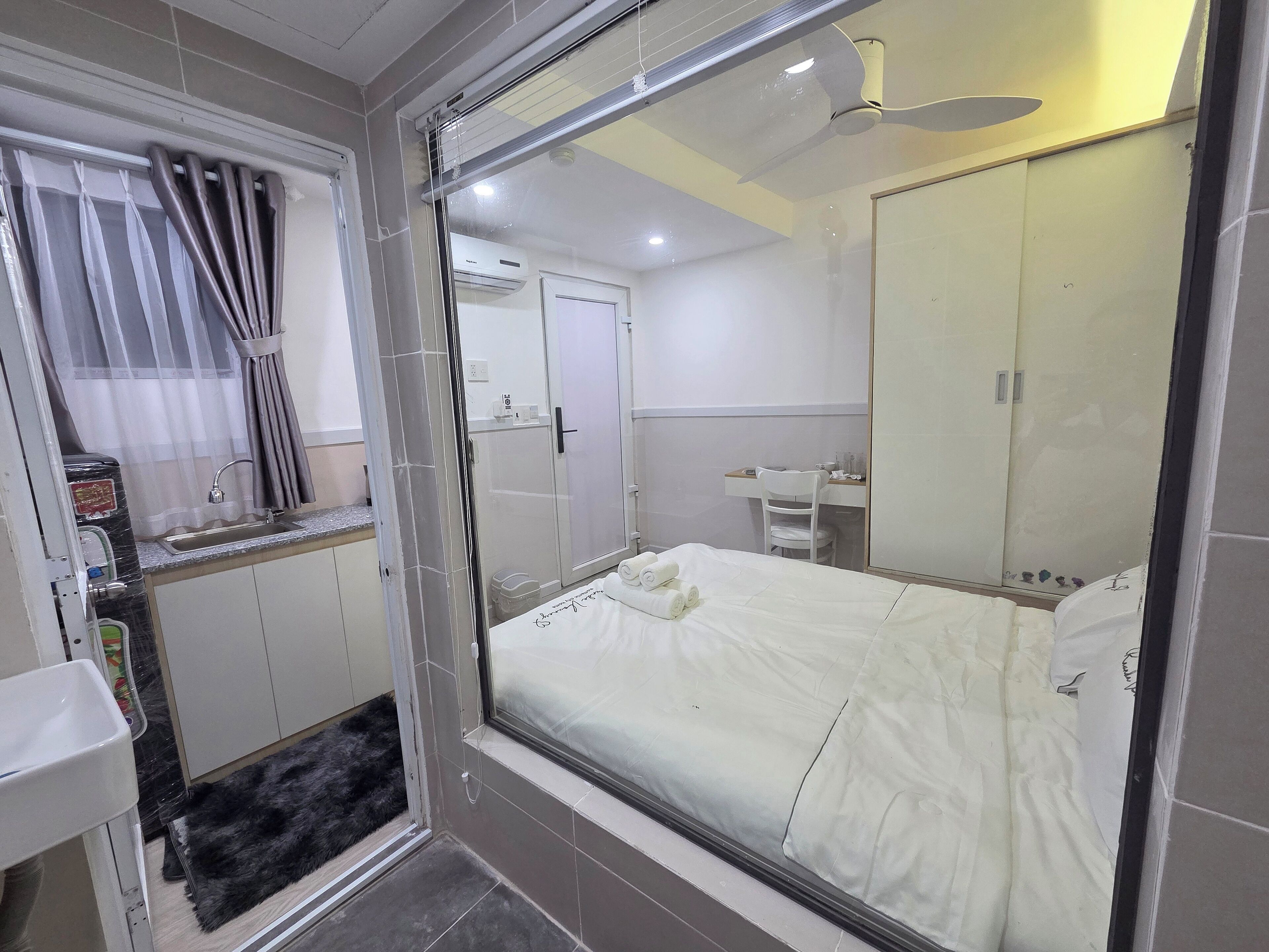 Ein Hotelzimmer mit Bett, Schreibtisch, Stuhl, Spiegel, Waschbecken und Duschbereich.