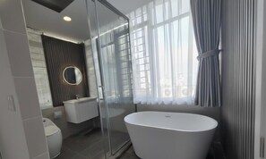 A modern bathroom with a freestanding bathtub, a glass shower enclosure, and a vanity with a mirror. - 1001 Stars (Ho Chi Minh City)