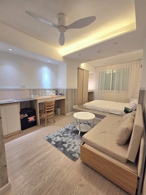A compact hotel room with a bed, a desk, a chair, a small round table, and a ceiling fan. - 1001 Stars (Ho Chi Minh City)