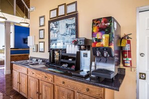 Een koffiehoek met een koffieapparaat, een fruitsapautomaat en een brandblusser.