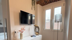 Ein modernes Wohnzimmer mit einer weißen Unterhaltungseinheit, einem Flachbildfernseher, einer Dekorationsvase und einer Stehlampe.