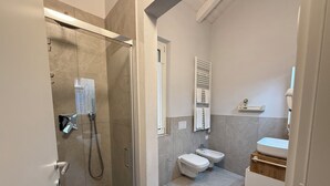 Ein modernes Badezimmer mit einer Glaskabine zur Dusche, Toilette, Bidet und Waschbecken.