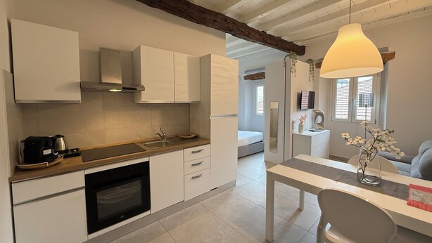 Eine moderne Küche mit weißen Schränken, einem eingebauten Backofen und einem Essbereich mit Tisch und Stühlen.