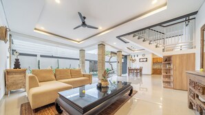 A spacious living area with a sofa, coffee table, and a staircase leading to an upper level. - Q LE Villas (Seminyak)