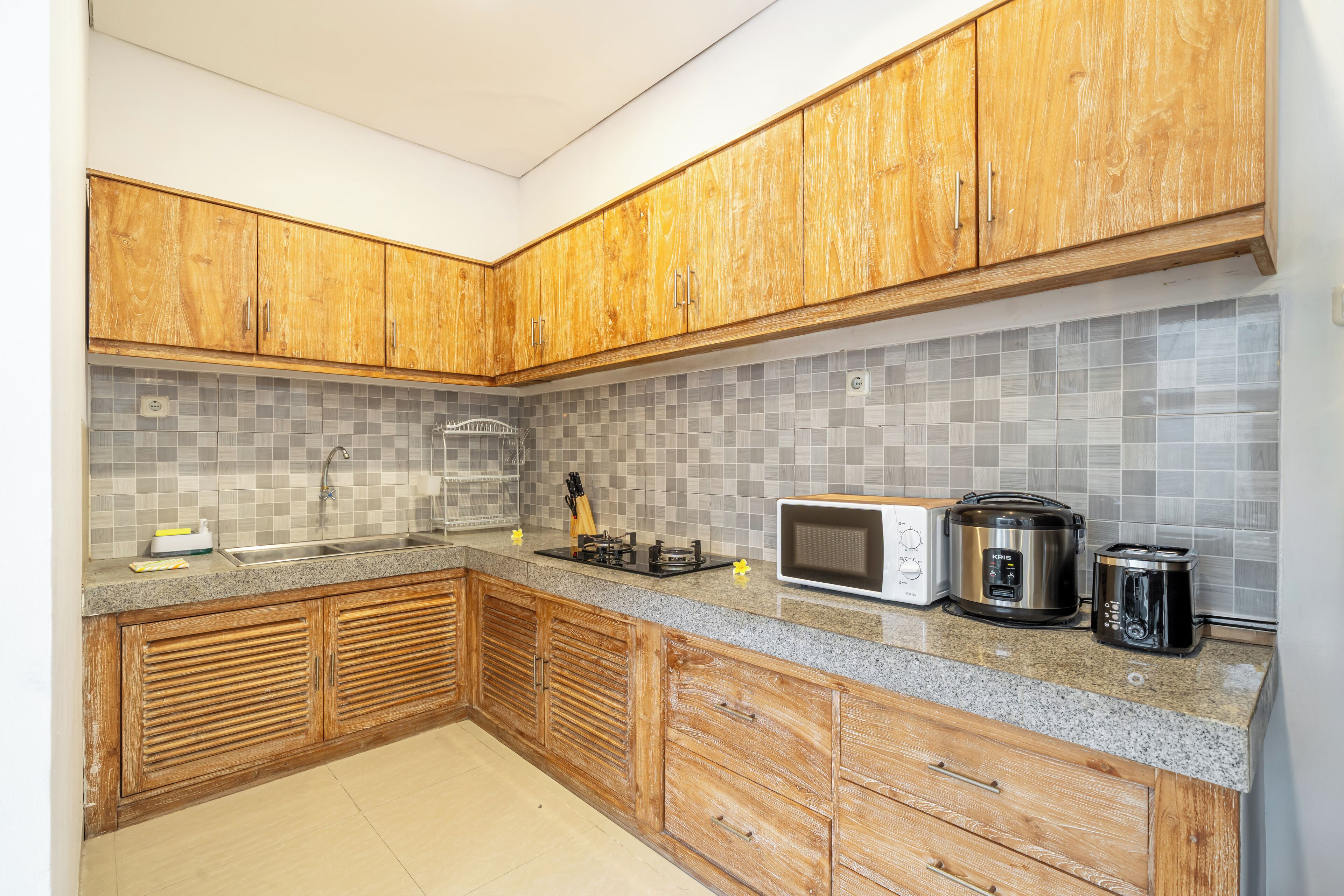 A kitchen with wooden cabinets, a granite countertop, a microwave, a toaster, and a kettle.