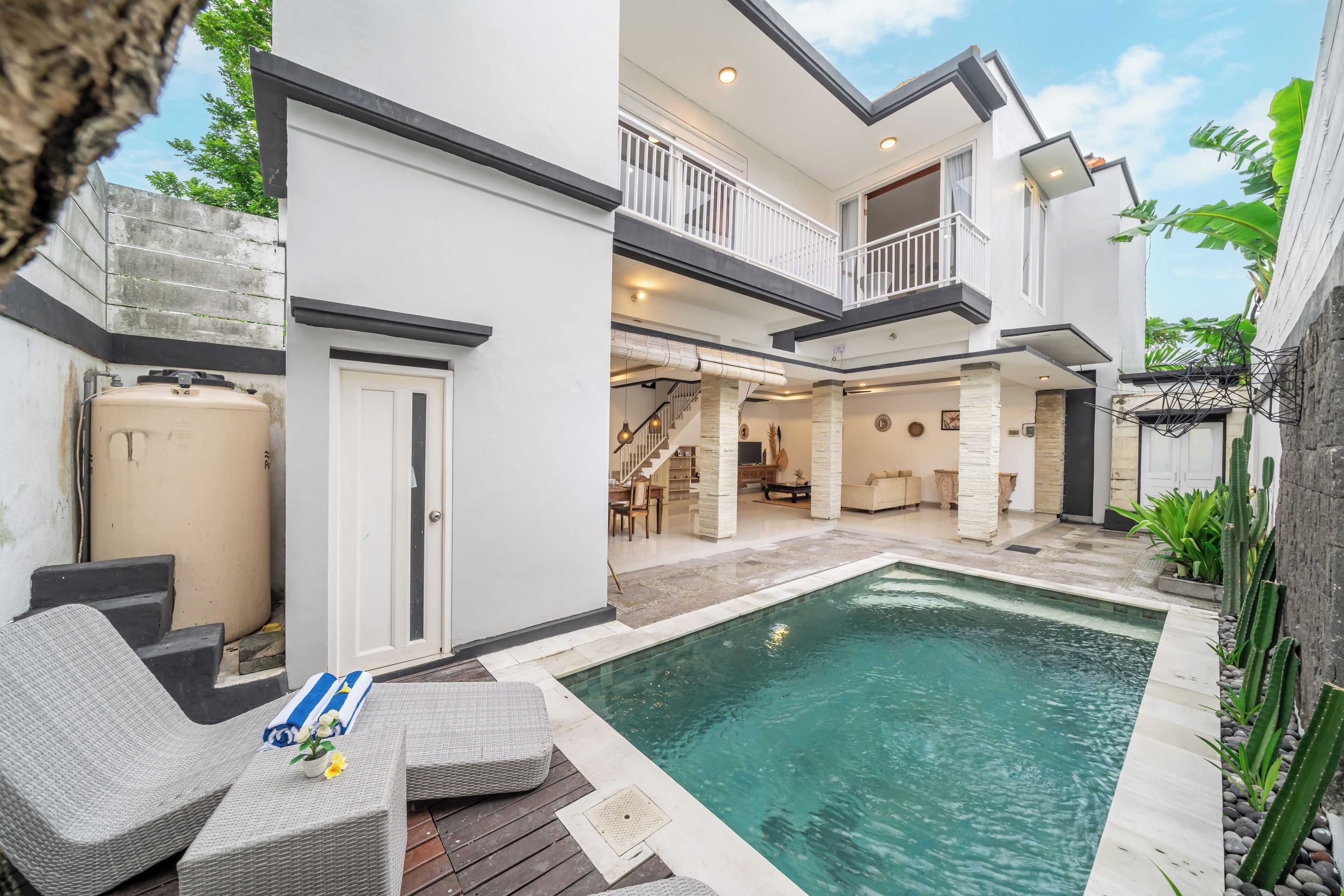 A modern two-story house with a swimming pool, outdoor seating, and a staircase leading to the upper level.