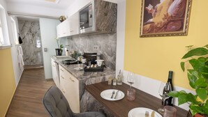 A modern kitchen with marble countertops, a microwave, and a dining area with a table set for two. - Deluxe 1‑BR Apartment Sleeps 3– Historic Palace, Heart of Prague (Prague)