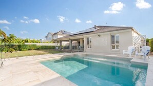 Una casa con piscina, un patio cubierto y vistas al vecindario.