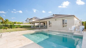 Una casa con piscina, un patio cubierto y vistas al vecindario.