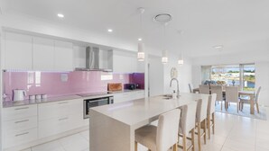 Een moderne keuken met witte kastjes, een centraal kookeiland met barkrukken en uitzicht op de omgeving.