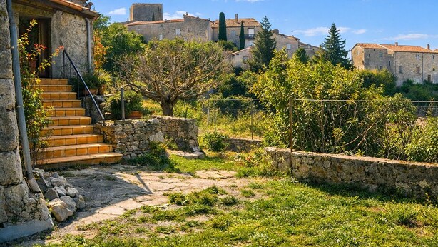 A stone building with a staircase leading to a door, surrounded by greenery and a stone wall. - In Balazuc, terrace overlooking the Ardèche gorges, 300 m from the beach. (Balazuc)