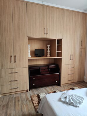 Une chambre avec une grande armoire, une télévision et un lit.