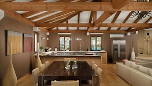 A modern kitchen with wooden beams, a dining area with wicker chairs, and a large island. - Malipiero Estate (Rovinj)