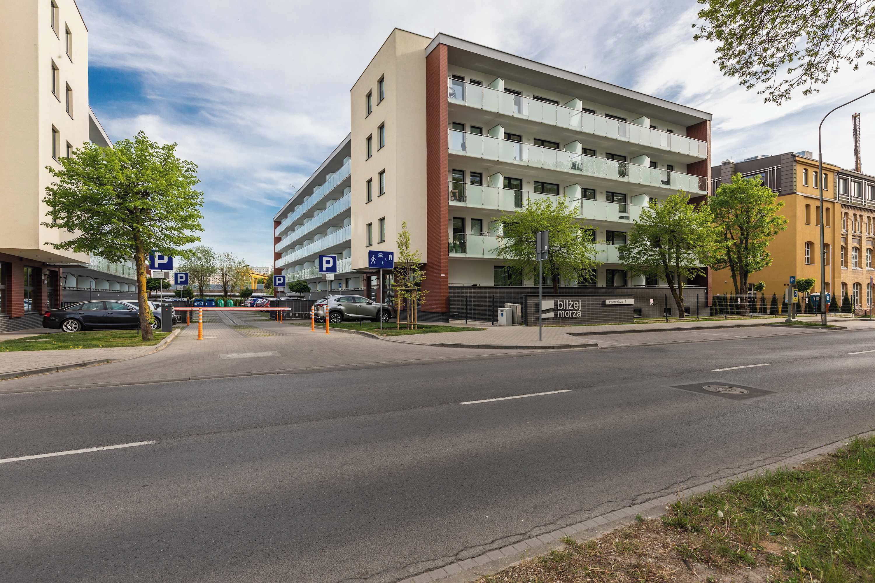 A multi-story building with a parking sign, a pedestrian crossing, and a clear road.