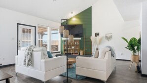 Ein modernes Wohnzimmer mit zwei weißen Sofas, einer Stehlampe und einer grünen Wand.