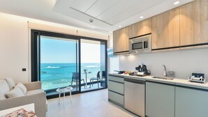 A modern kitchen with a view of the ocean, a dining area with a sofa and table, and a large sliding glass door. - OH Suites Paseo de las Canteras 58 (Las Palmas de Gran Canaria)