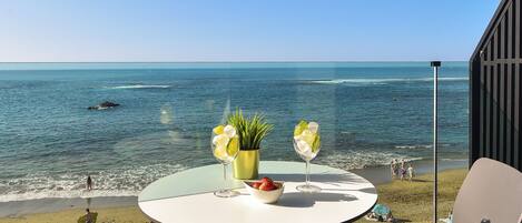 A balcony with a table and chairs overlooking a beach.