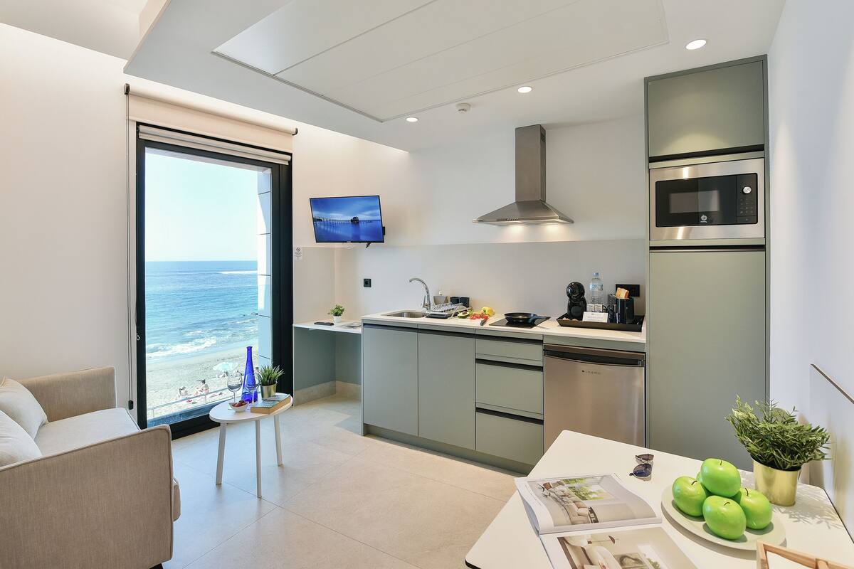 A modern kitchen with a large window, a flat-screen TV, and a dining area with a table and chairs.