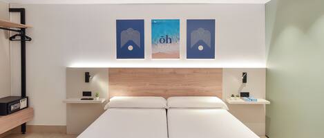A modern hotel room with a large bed, a wooden headboard, bedside tables with lamps, and artwork on the wall.