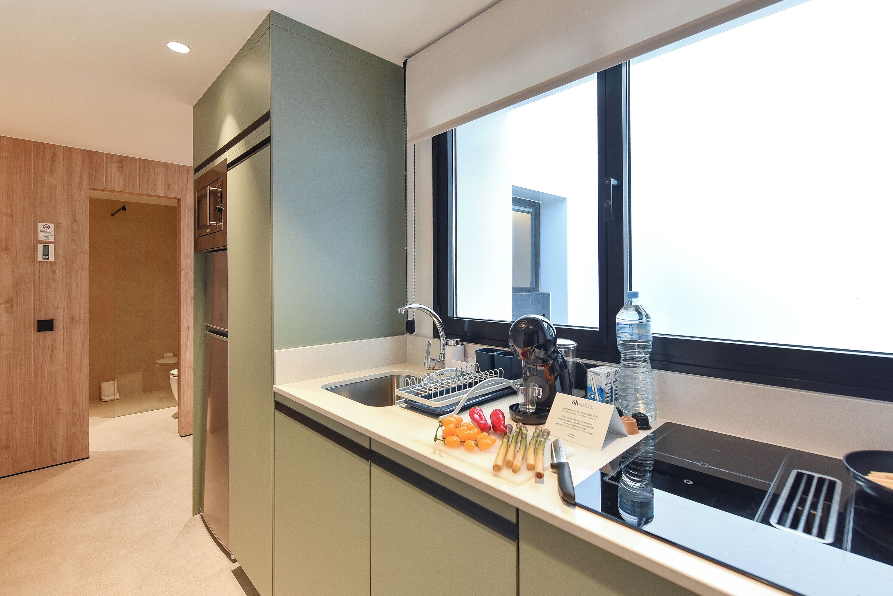 A modern kitchen with a built-in dishwasher, a window with a view, and a countertop with various items.