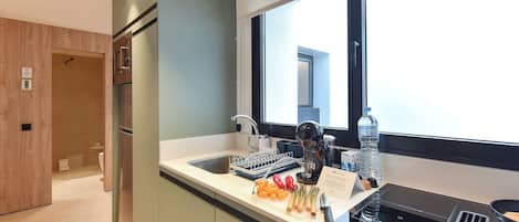 A modern kitchen with a built-in dishwasher, a window with a view, and a countertop with various items.