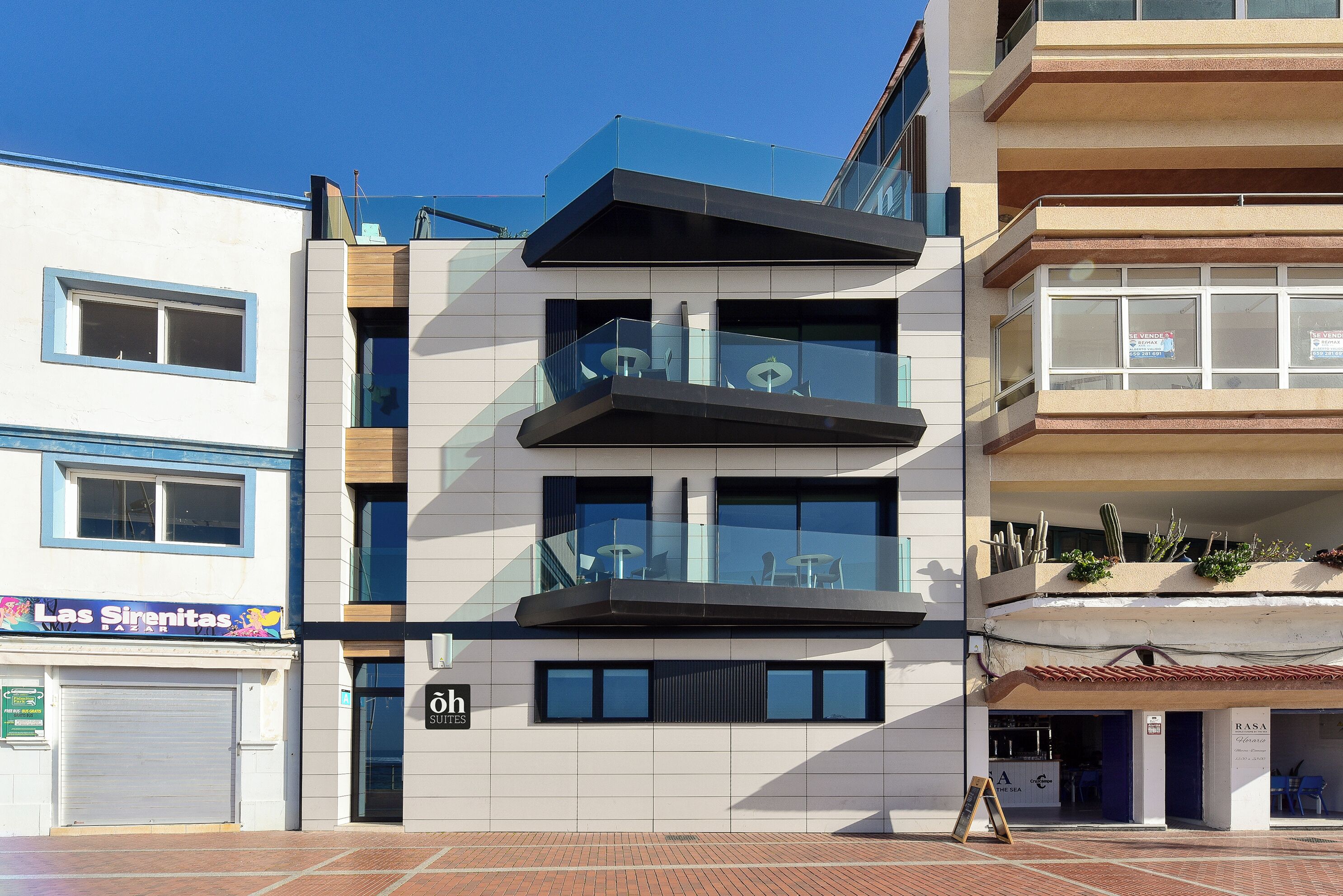 A modern building with multiple balconies, large windows, and a sign for 'Las Sirenitas'.