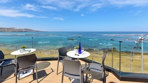 A terrace with a table and chairs overlooking a beach and the sea. - OH Suites Paseo de las Canteras 58 (Las Palmas de Gran Canaria)