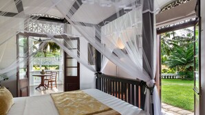 A bedroom with a bed, a table, chairs, and a view of a garden through an open door. - Clingendael Weligama (Weligama)