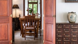 A wooden dining area with a table and chairs, a cabinet with drawers, and a framed picture on the wall. - Clingendael Weligama (Weligama)